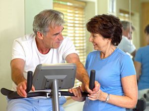 Man on exercise bike with his wife